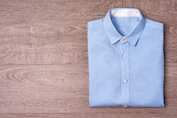 New man's shirt blue on wood background.