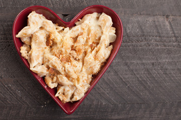 Freshly made pasta with creamy sauce and breadcrumbs on top in heart bowl
