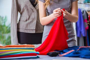 Fototapeta premium Young woman tailor working in workshop on new dress