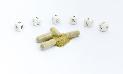 Close up andrographis paniculata herbal antipyretic capsules with Wooden Blocks text: "Herbal"