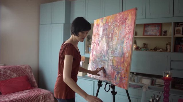 Woman artist painting an abstract painting of the hands in the art studio. 4 k