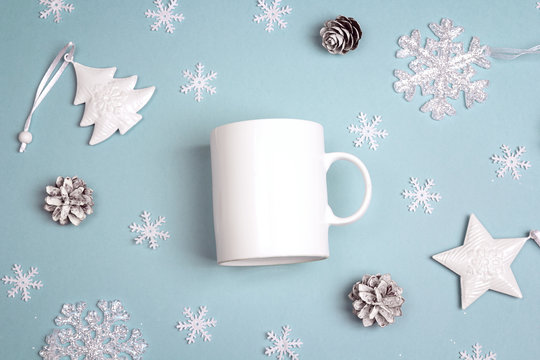 White coffee mug  with Christmas decorations on blue background. Space for text or design.