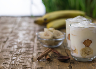 Banana pudding with cream, biscuits and cinnamon on vintage table.