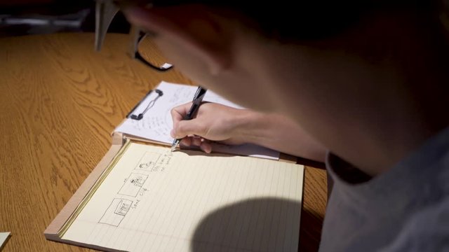 Over the shoulder shot of a story board in production by a white teen male boy.