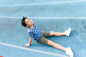Boy rest on the blue track after sport
