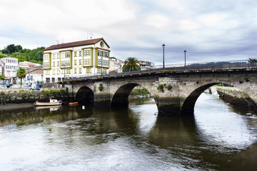 Roman bridge over the Ria de Betanzos with a strong current and in the middle of a town in Galicia,...