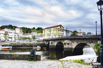 Roman bridge over the Ria de Betanzos with a strong current and in the middle of a town in Galicia, Spain