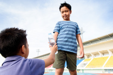 Boy give water to another boy