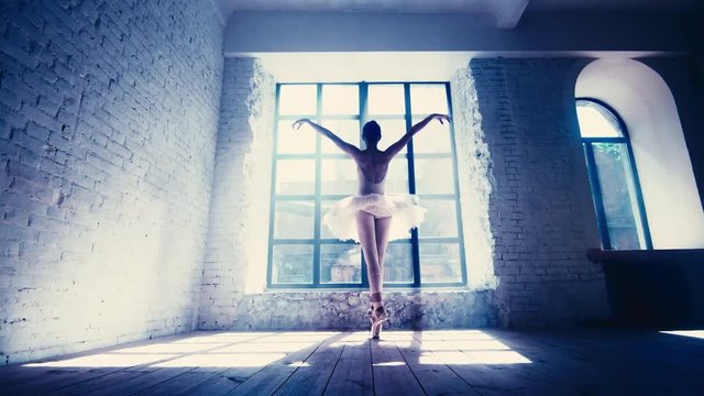 Practicing female ballet dancer in loft style room near the window