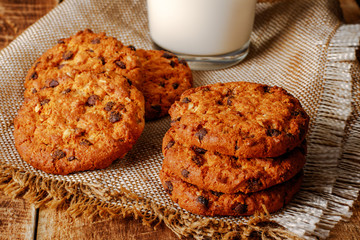 Chocolate chip cookies with milk on wooden background
