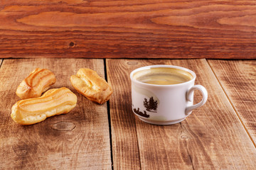 Cake eclair with chocolate icing, cup of coffee, chocolate, on a black background