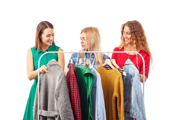 Three young woman browsing through clothes on rack