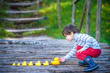 Adorable child, boy, playing in park with rubber ducks, having fun. Childhood happiness concept