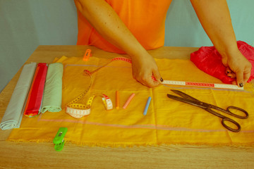 closeup of woman hands sewing yellow cloth outdoors