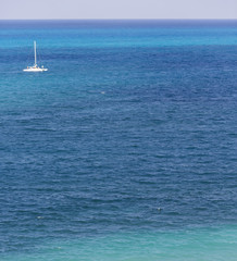 Obraz premium Boat sailing in the middle of the sea. Focus point on the low part of image. Sail boat out of focus.