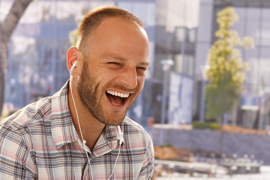 Happy man laughing with earbuds