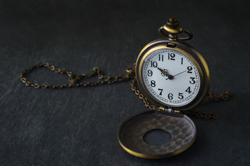 Vintage pocket watch on black stone background