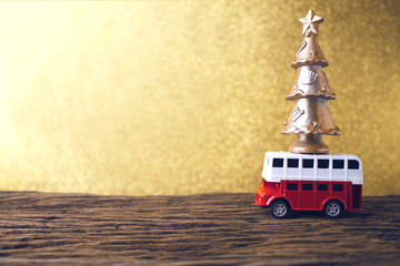 gold christmas tree on car bus toy with bokeh background and wood table