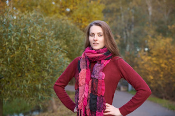 young girl with long hair and white skin walks in autumn Park, portrait in natural color, gaze is directed in camera. hands rested in the thigh