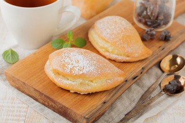 Pasties with cottage cheese and powdered sugar on a light wooden background. Traditional Russian pastry Sochnik. Selective focus. .