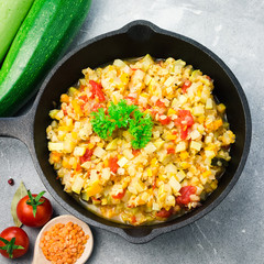 Sauteed vegetables zucchini squash tomato carrot onion lentil in cast iron skillet. Vegan side dish. Top view, copy space.