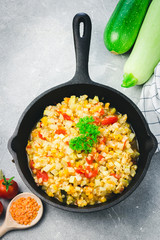 Vegan sauteed vegetables in cast iron skillet on concrete background. Top view, copy space.
