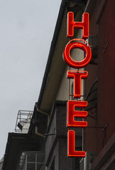Illuminated red text hotel. Small cheap hotel. Text Hotel on facade.