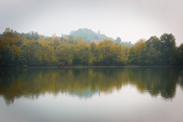 Fototapeta na wymiar Fall Trees and Lake Reflection on a Foggy Morning