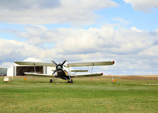 small airplanes an-2 on the aerodrome, angar on the background. Airplane in the sky