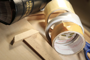 Still life stationery theme. Scissors, tape, ruler lying on wooden surface.