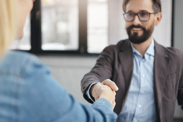 Focus on hands. Business partners make handshake being in office, close deal or partnership,...