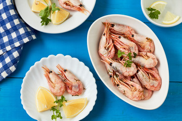 Prepared shrimps on white plate with parsley and slices of lemon. Top view