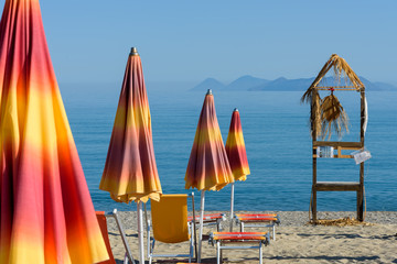 Morning view of the sea with Eolian Island in the background and umbrellas on the beach in Bazia, Furnari, Messina - Sicily