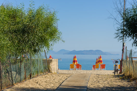 Morning view of the sea with Eolian Island in the background and umbrellas on the beach in Bazia, Furnari, Messina - Sicily