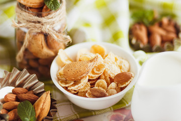 Honey in the bowl, muesli, mint leaves, almonds and jar with milk on the wooden tray