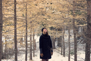 Fototapeta na wymiar girl in black coat, black wool hat and scarf in the winter forest