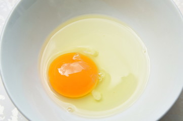 raw yolk and white egg cracked from shell in cup