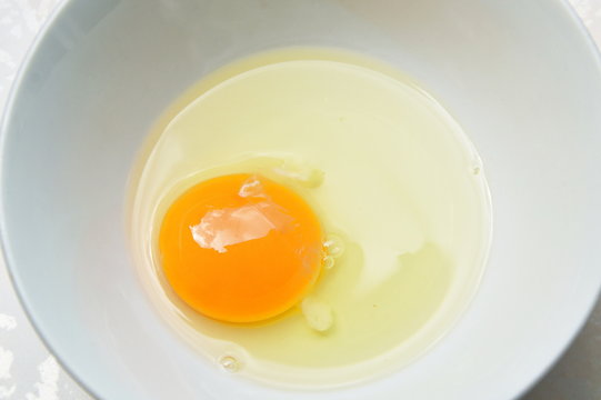 raw yolk and white egg cracked from shell in cup