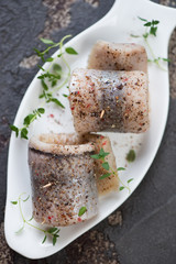 Closeup of herring rolls with fresh thyme and spices on a white plate, high angle view