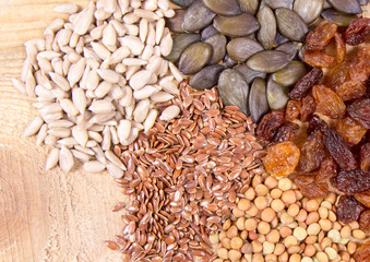 Flaxseed, pumpkin, raisins, lentils and sunflower seeds in wooden spoons.