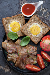 Fried bacon with eggs in the basket and tomato, view from above, vertical shot
