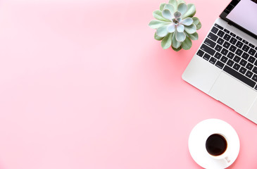 Working with Laptop computer,Hot coffee and cactus copy space on pink table background.Top...