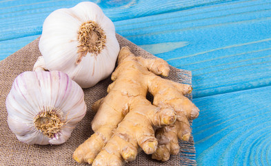 Garlic bulbs with ginger on blue wooden table. Concept of natural medicine.