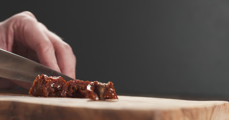 closeup man slicing sundried tomatoes
