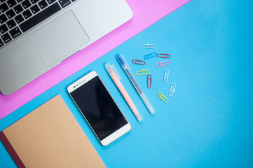 Top view of work desk.Laptop with notebook ,coffee,smartphone on colorful minimal flatlay background