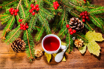 ashberry tea in a white cup. fir branches with rowan on a wooden board. Christmas theme.