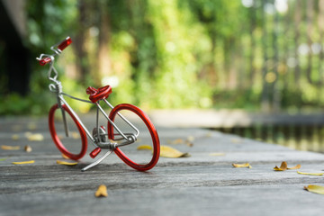 Toy red bicycle on wood floor, in the beautiful park background.
