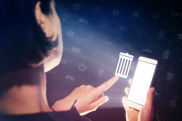 Image of a girl with a smartphone in hands. She presses on the trash can icon. The concept of deleting files, contacts, putting in order, cleaning service etc.