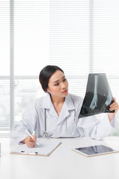 Beautiful asian female doctor examining Xray report in clinic