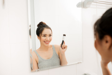 Obraz na płótnie Canvas Beautiful woman applying makeup blusher in her bathroom